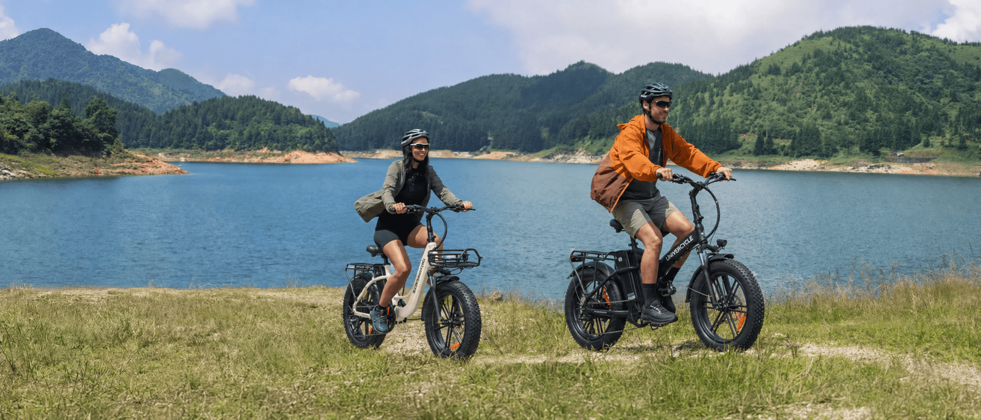 A rider exploring a scenic European trail on a black Univercycle folding fat tire electric bike with beautiful mountains in the background.